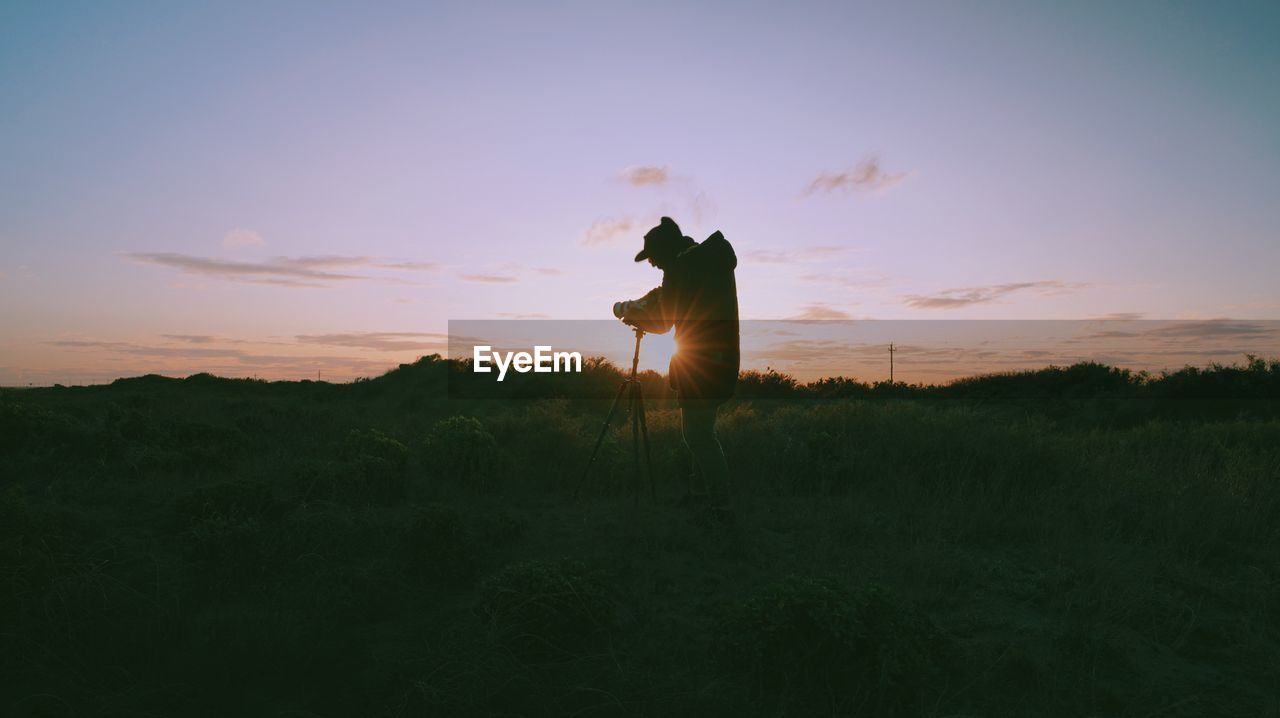 Low angle view of person on field against sky during sunset