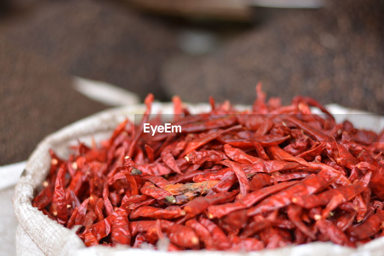 Close-up of dried red chili peppers in sack at market stall
