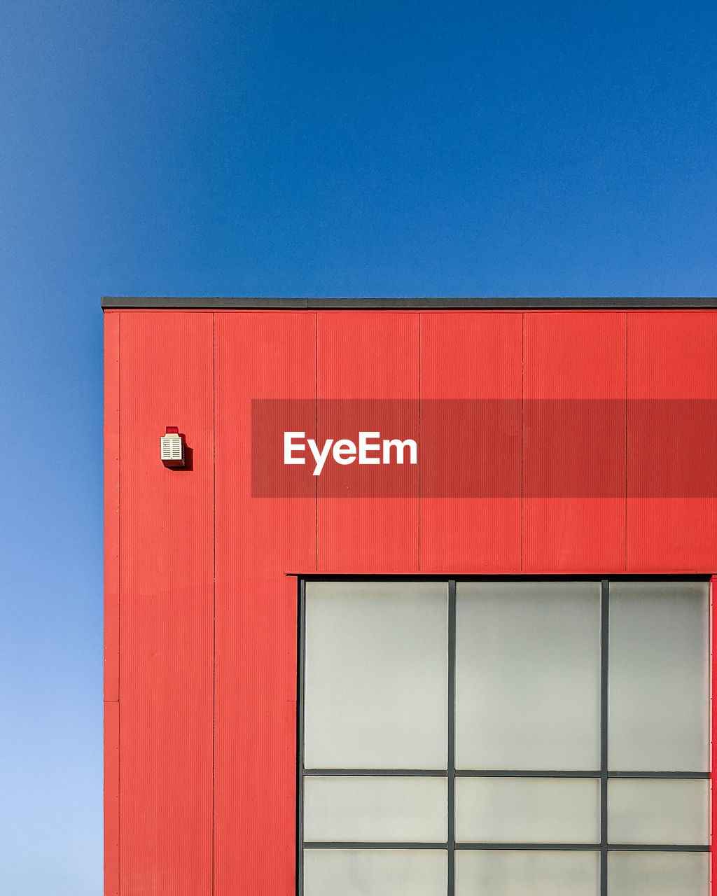 Low angle view of red building against clear blue sky