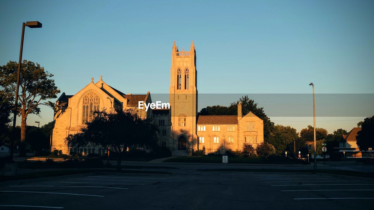 Sunlight falling on historic church in city against blue sky