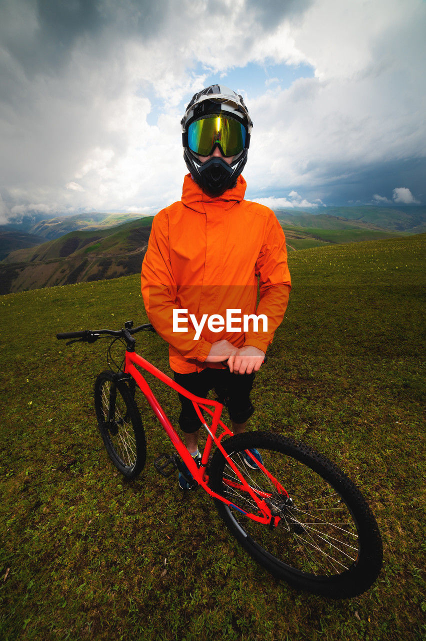 Wide angle vertical frame top angle. portrait of a bearded mountain biker with his bicycle against a