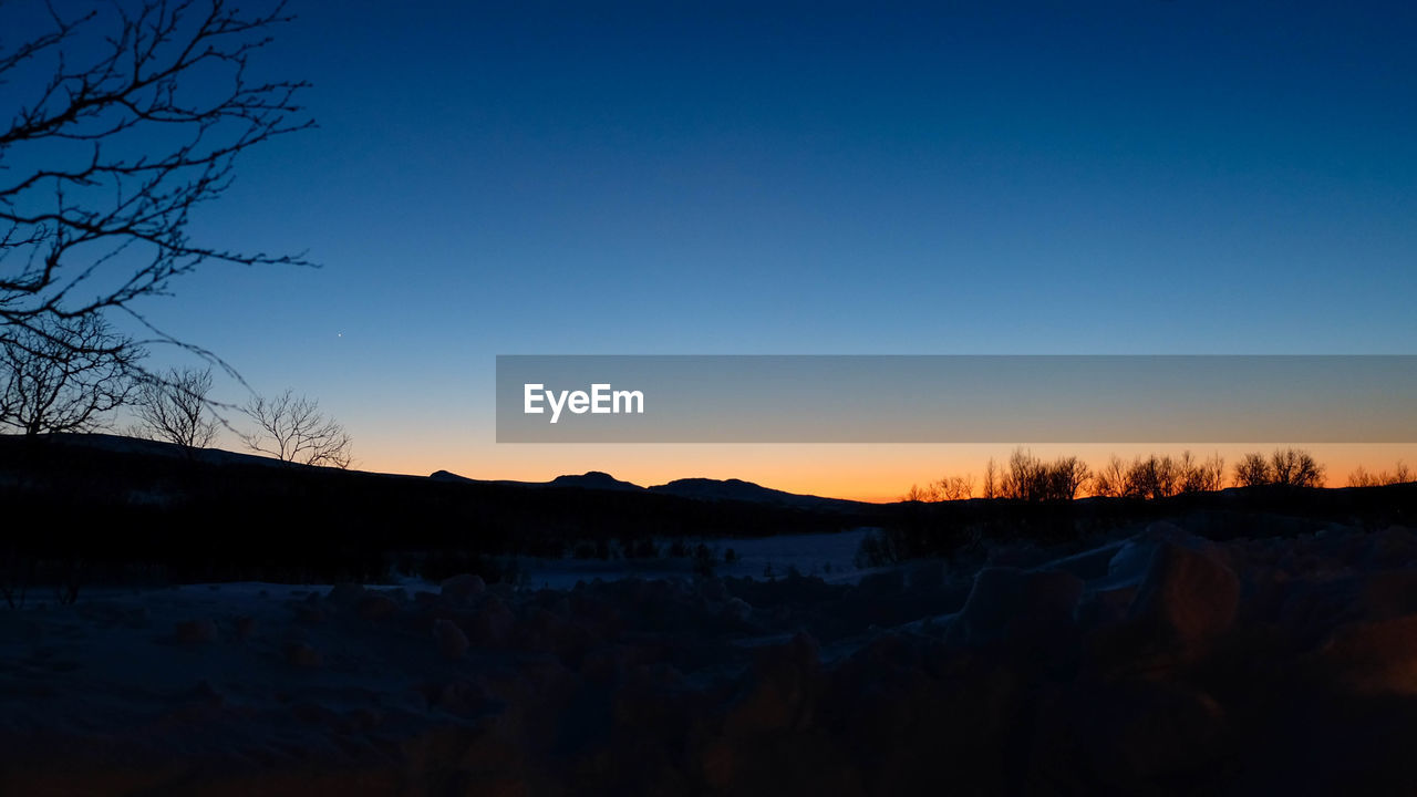 SILHOUETTE LANDSCAPE AGAINST CLEAR SKY DURING SUNSET