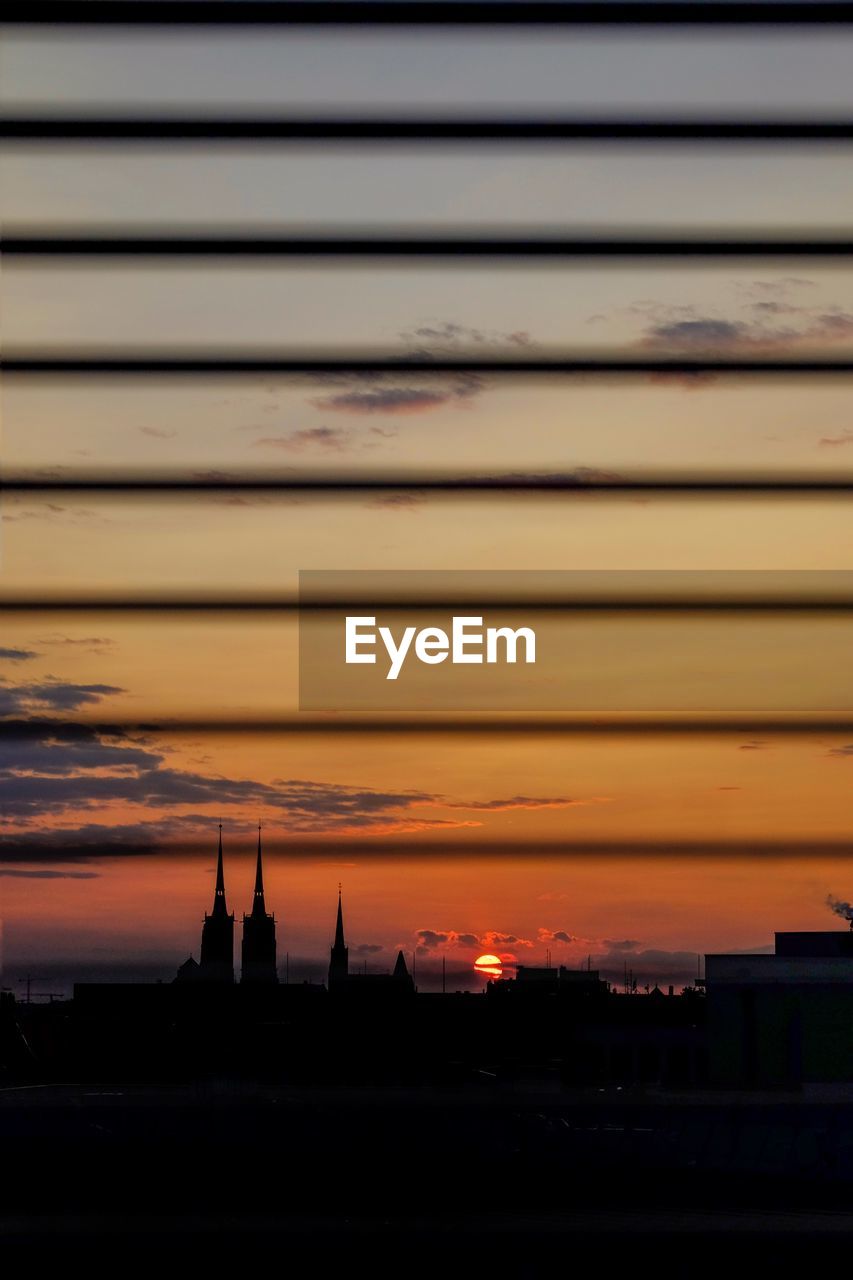 CLOSE-UP OF SILHOUETTE CITY AGAINST ORANGE SKY