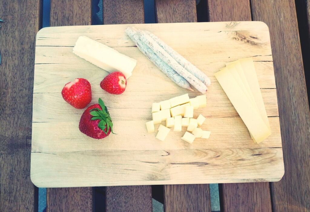 High angle view of strawberry with cheese and herb stick on cutting board