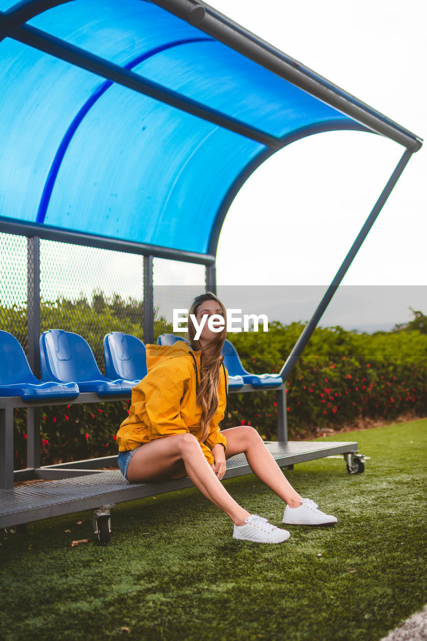 Portrait of woman sitting on seat in city
