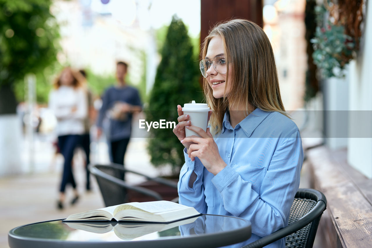 young woman using mobile phone while sitting at park