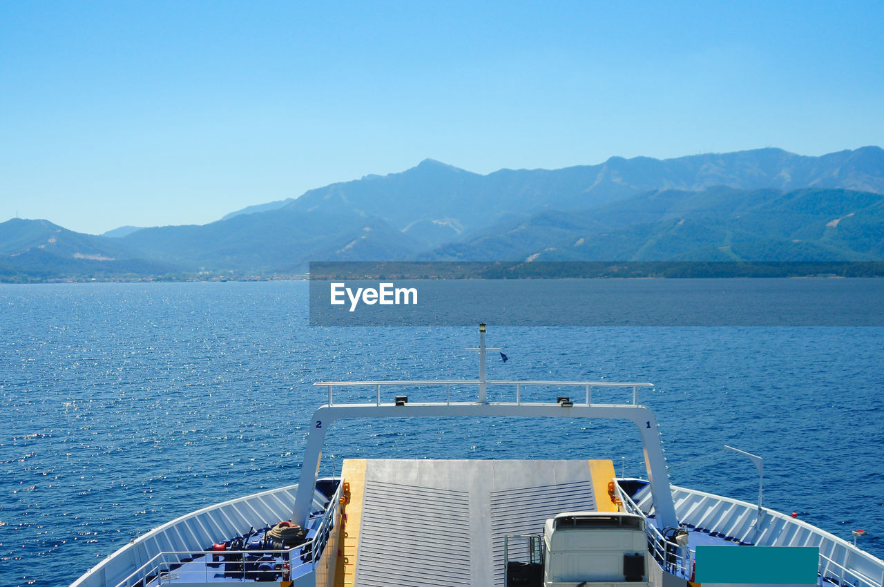 SCENIC VIEW OF SEA BY MOUNTAINS AGAINST CLEAR BLUE SKY