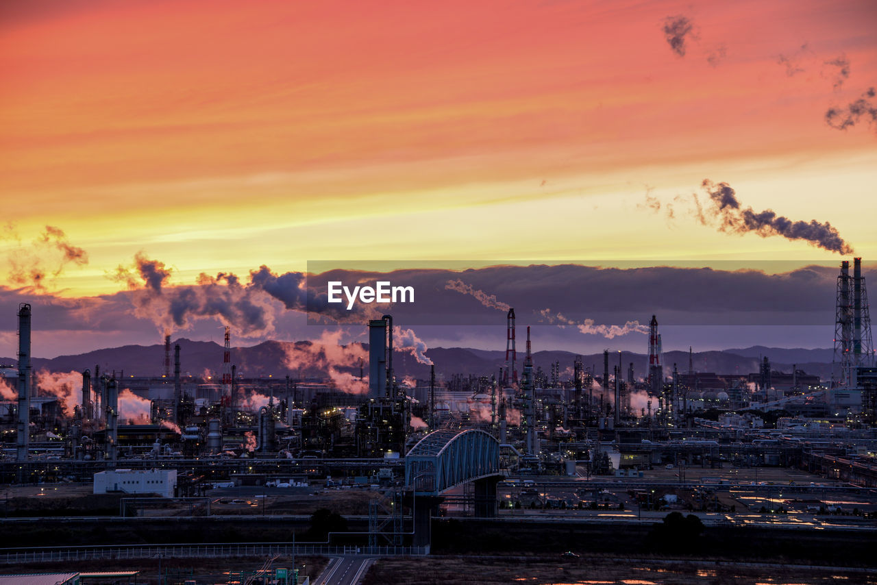 Illuminated factory against sky during sunset 