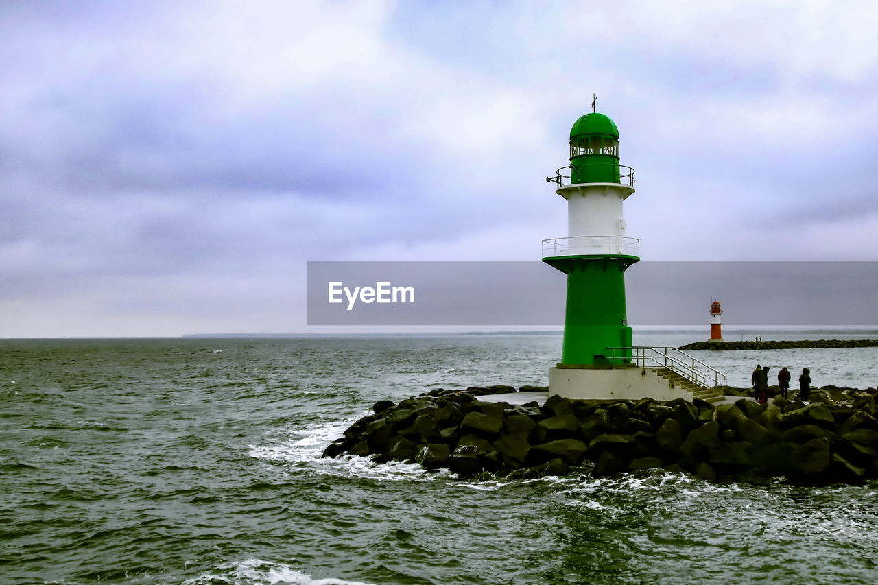 Lighthouse by sea against sky