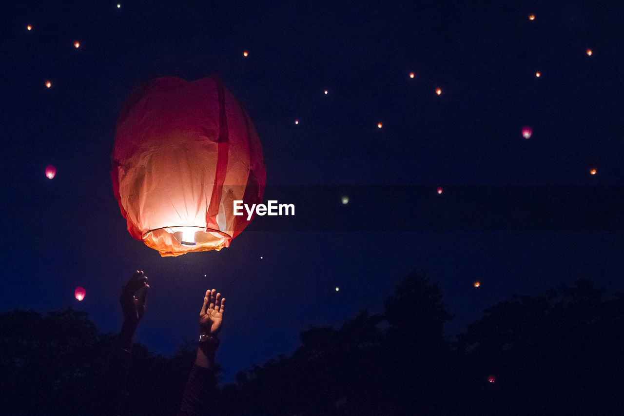 Low angle view of illuminated lantern against sky at night