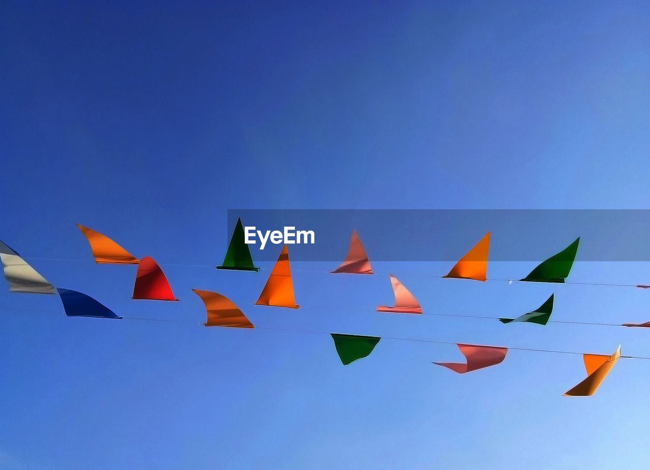 LOW ANGLE VIEW OF FLAGS AGAINST BLUE SKY