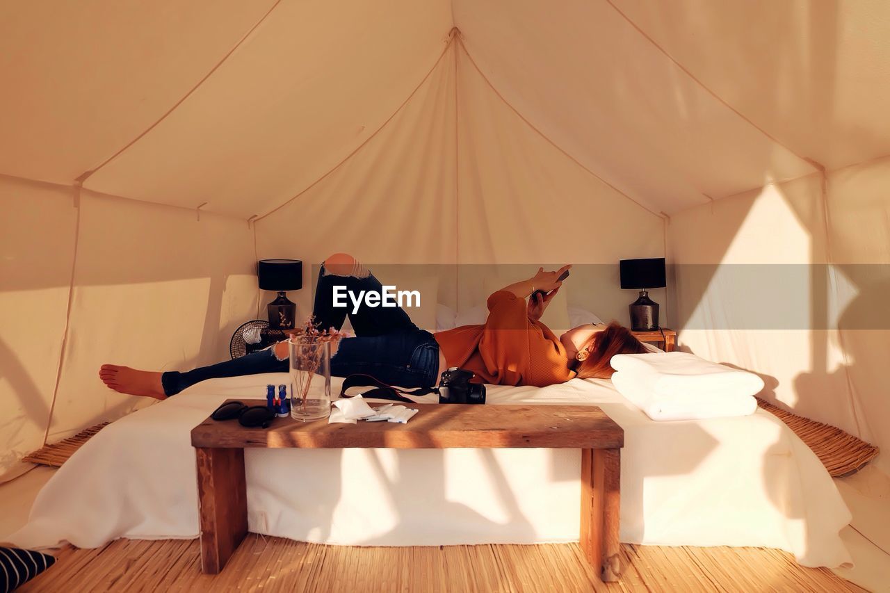 Woman relaxing on bed in tent