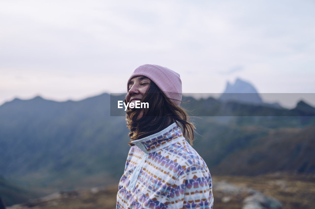 Smiling woman wearing knit hat standing on mountain around ibones of anayet