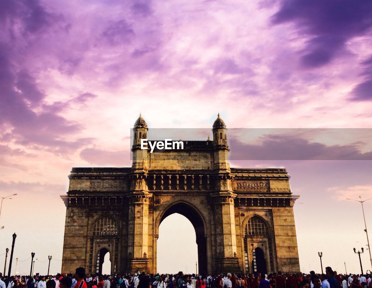 People at gateway of india against cloudy sky