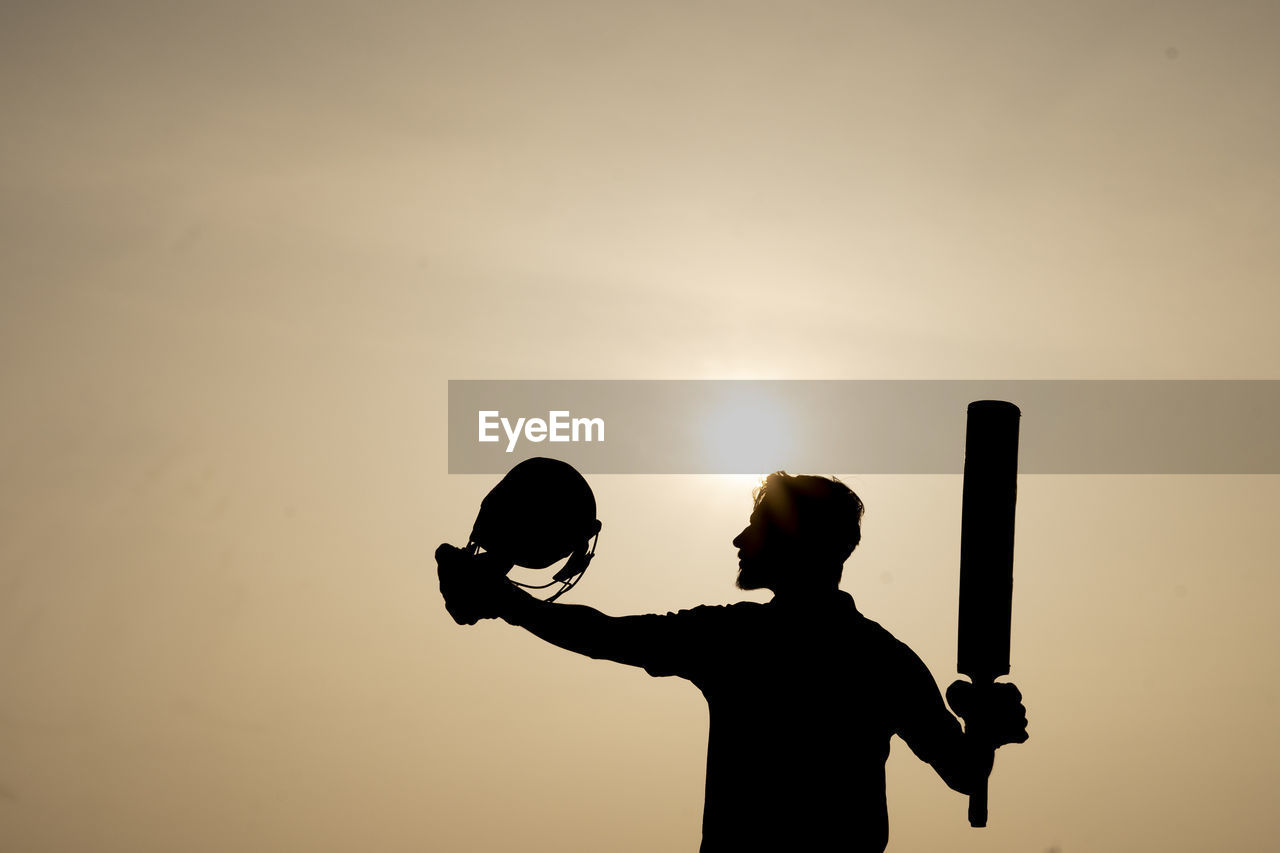 Silhouette of a cricketer celebrating after getting a century in the cricket match. indian players