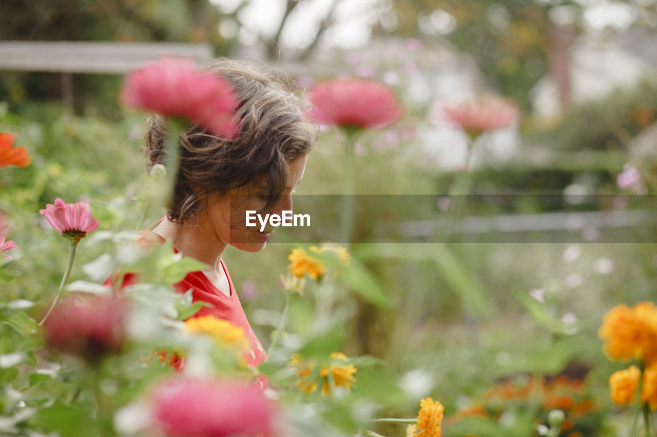 A woman stands half-hidden in beautiful patch of wildflowers in summer