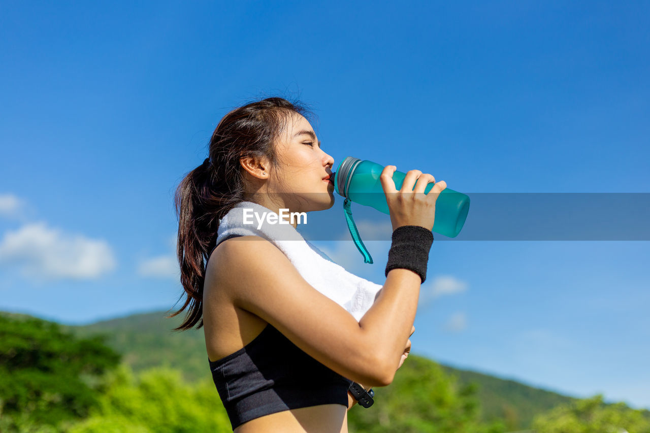 FULL LENGTH OF WOMAN STANDING AGAINST BLUE AND SKY