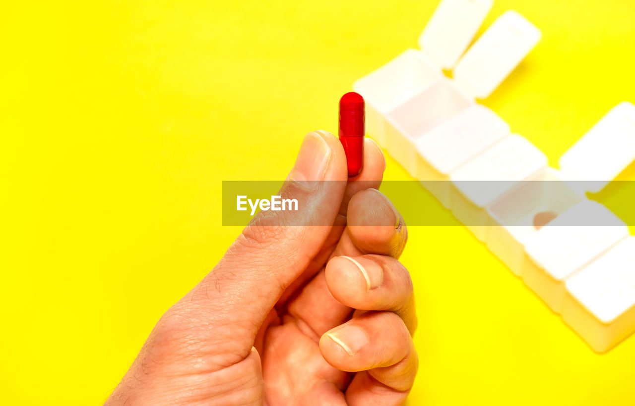 hand, yellow, finger, colored background, studio shot, indoors, holding, one person, adult, close-up