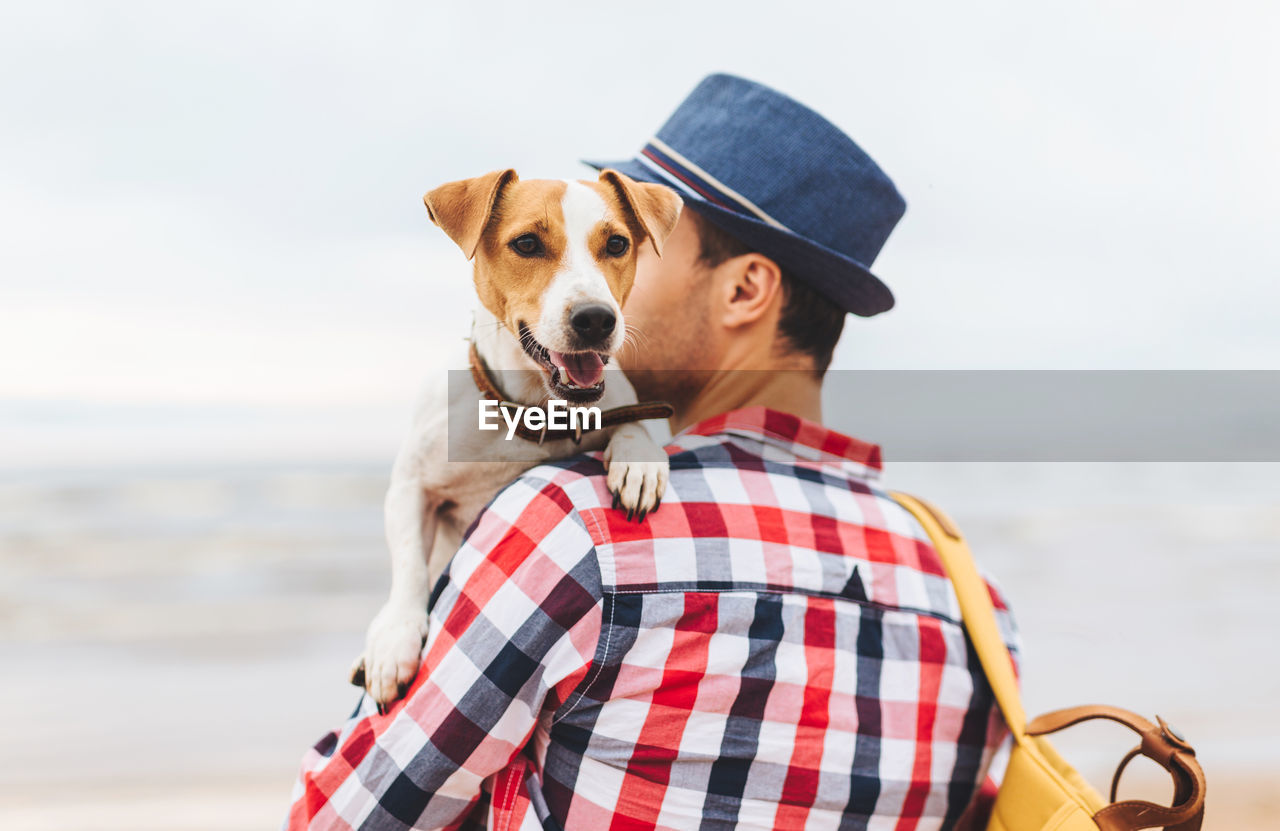 PORTRAIT OF DOG BY SEA AGAINST BEACH