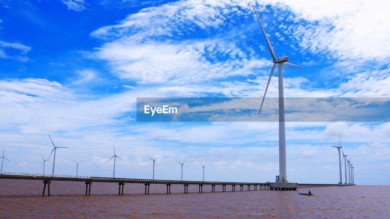 Low angle view of windmills against sky