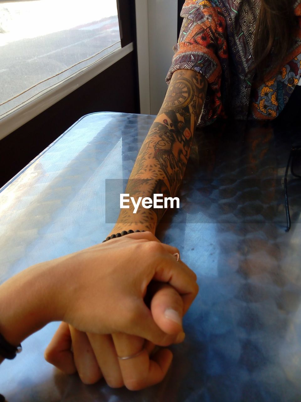 Cropped image of friends holding hands at table