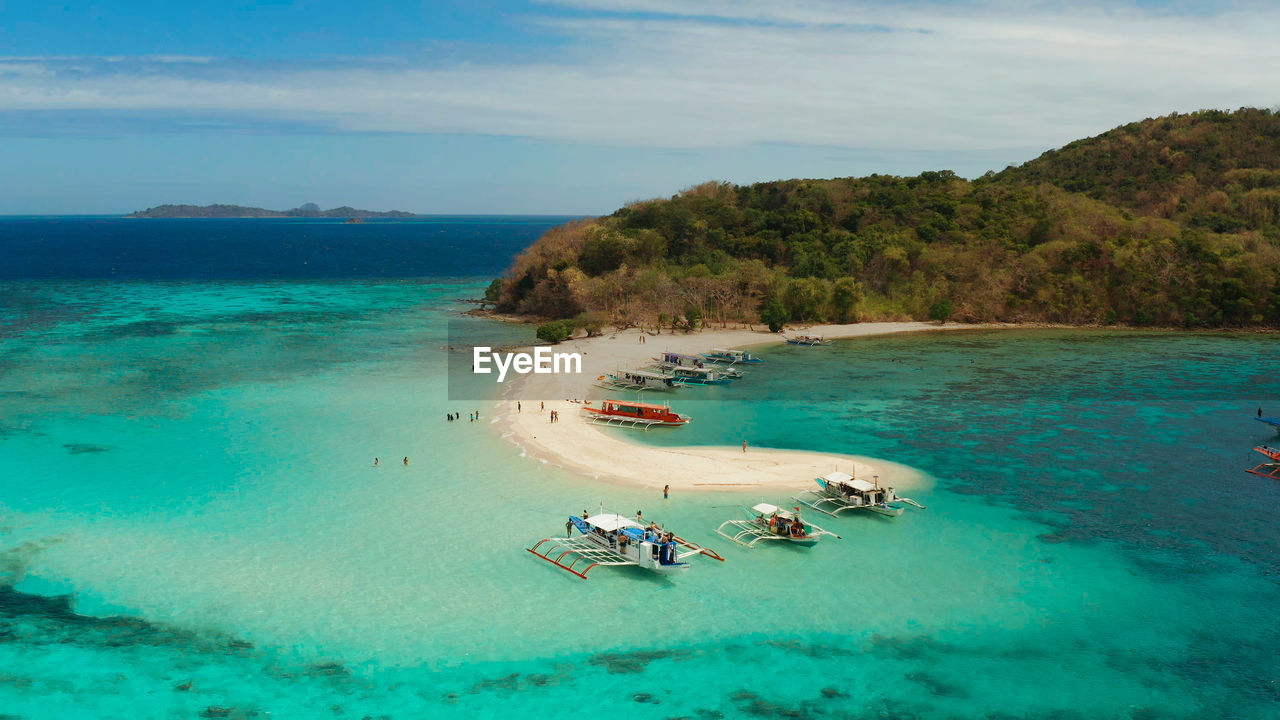 Tropical beach on island ditaytayan. tropical island with white sand bar, palm trees and green hills