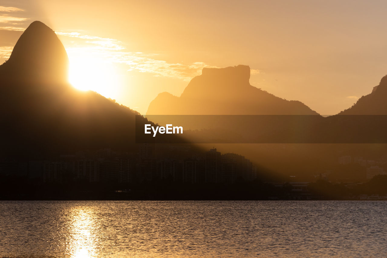 Scenic view of sea and silhouette mountains against sky during sunset