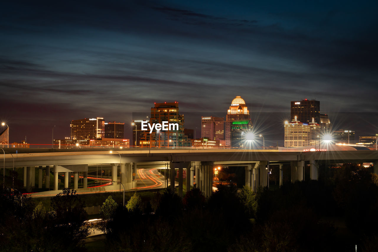 Illuminated modern buildings in city against sky at night