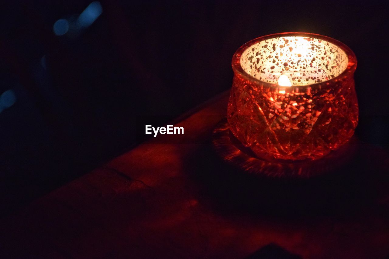 Close-up of illuminated candle in container on table