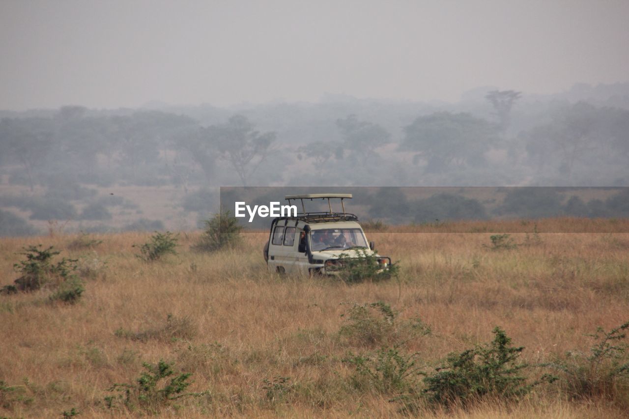 Abandoned car on field against sky