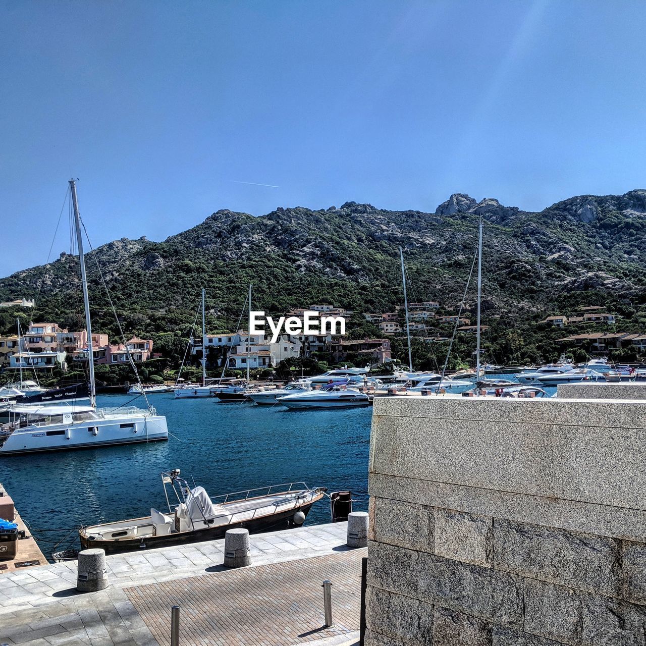 SAILBOATS MOORED AT HARBOR AGAINST CLEAR SKY