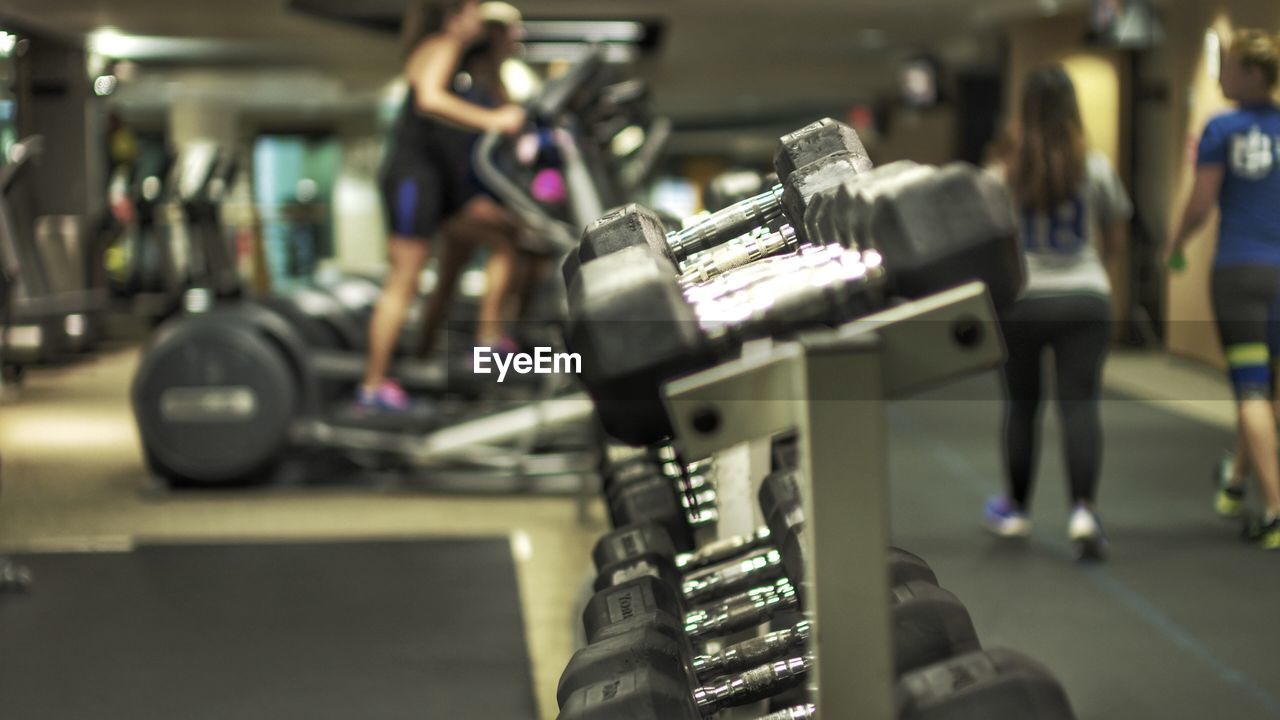 Dumbbells on rack with people in background at gym