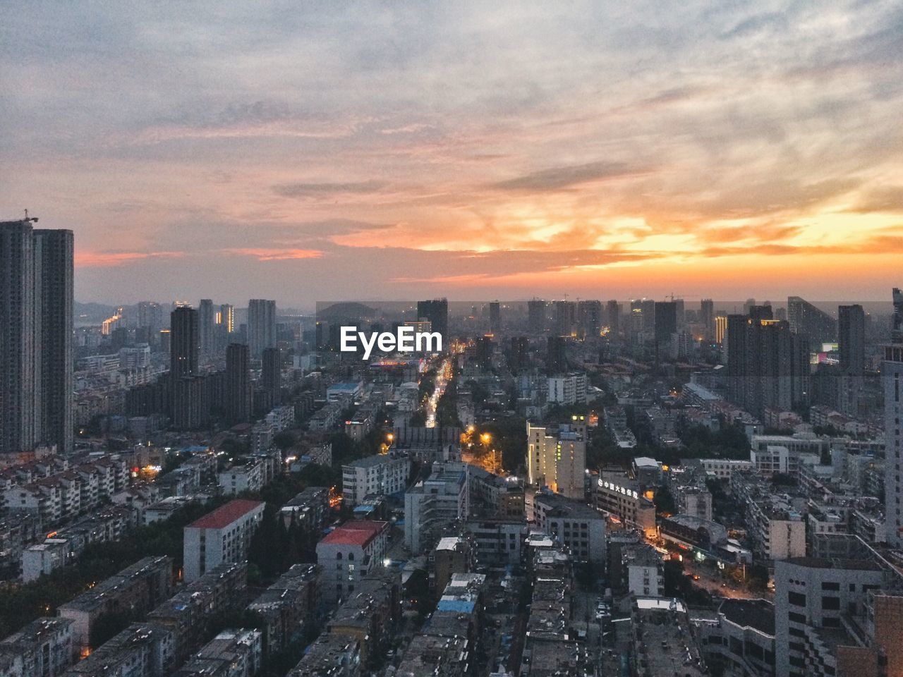 High angle view of illuminated cityscape against cloudy sky