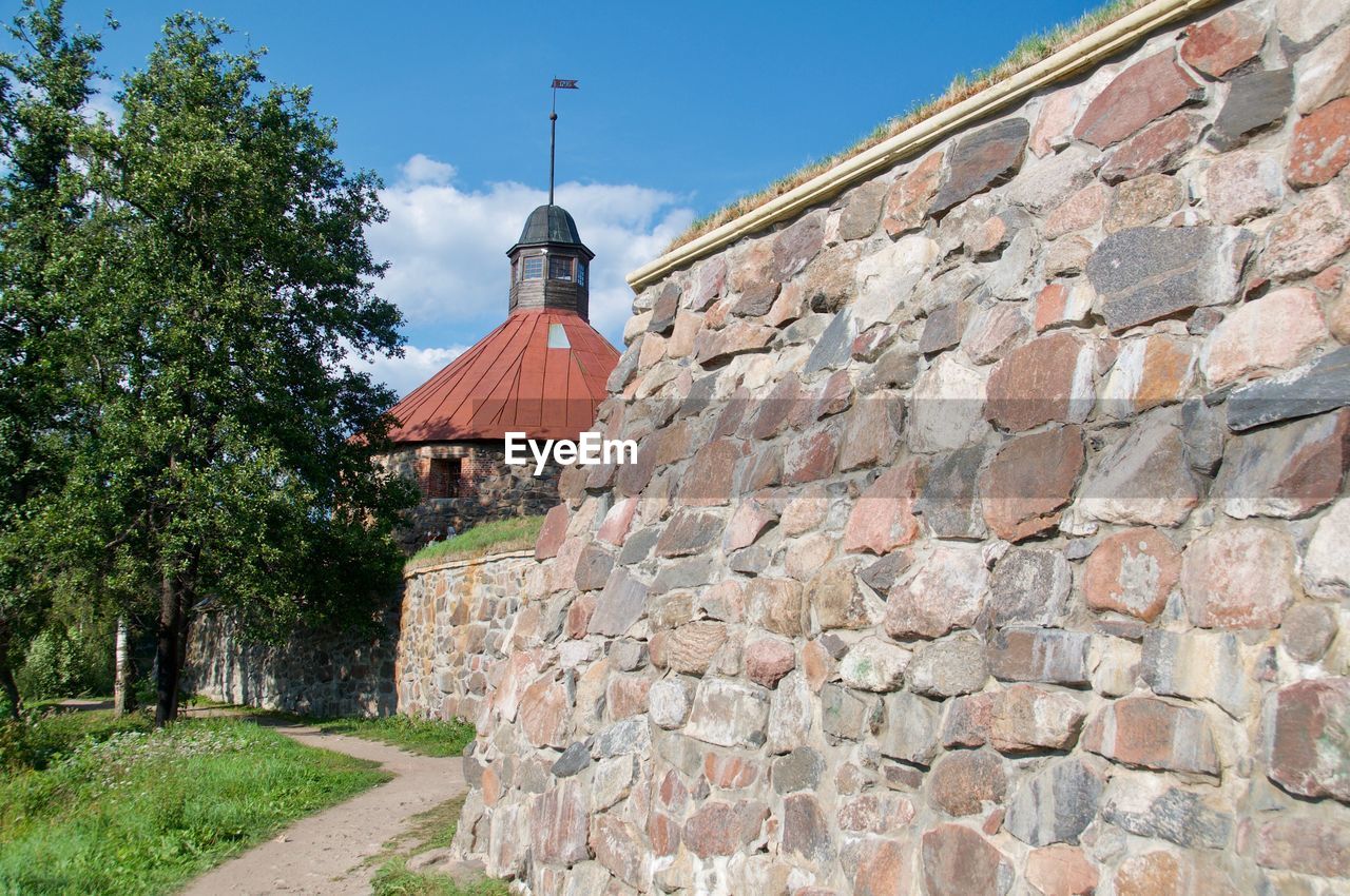 Brick wall by building against sky