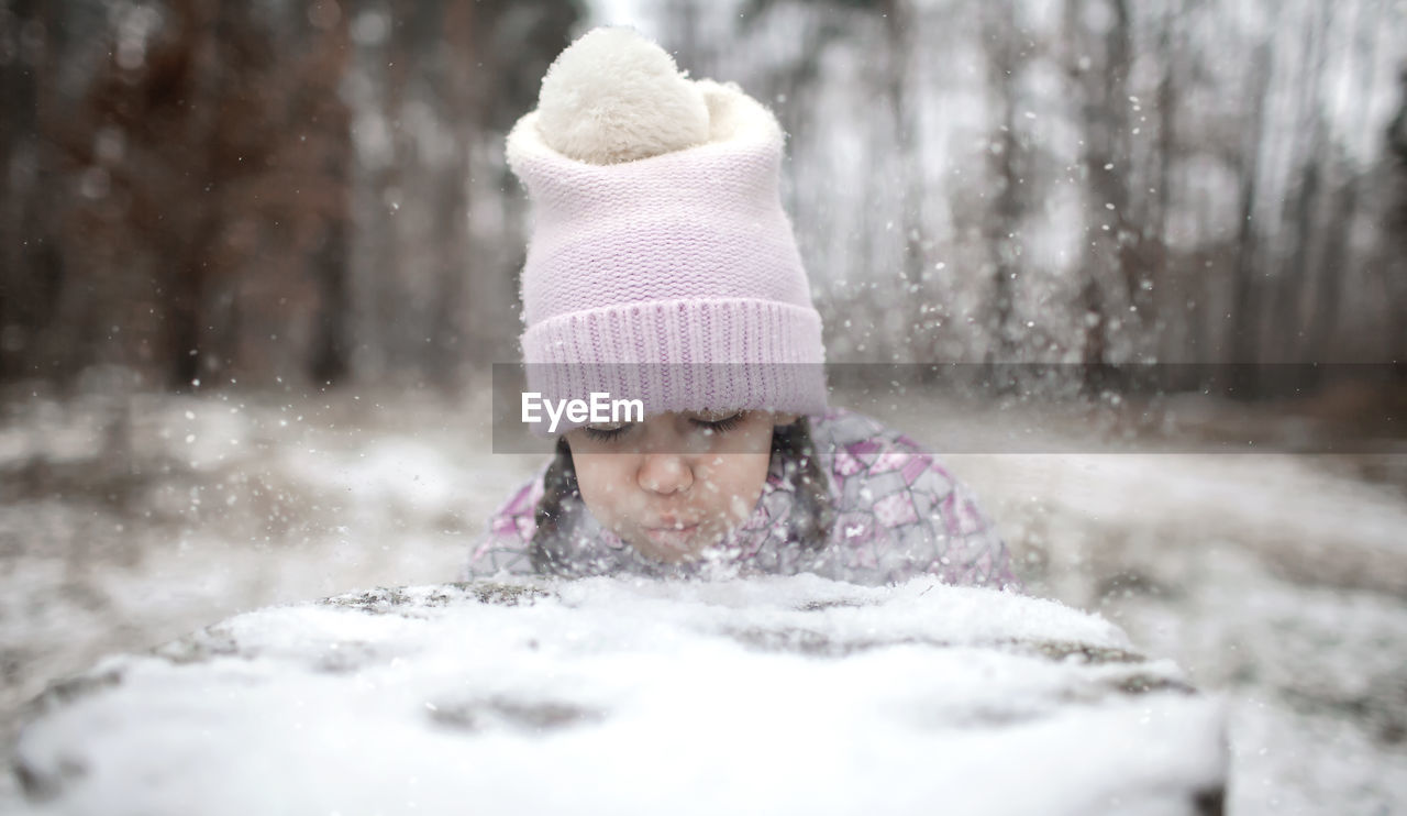 Cute girl blowing snow during winter