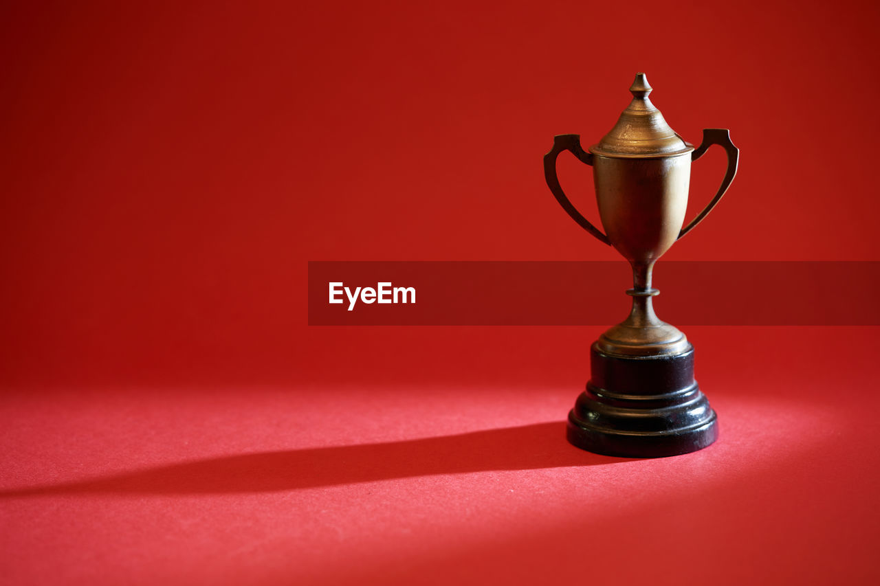 Antique metal gold trophy on red background