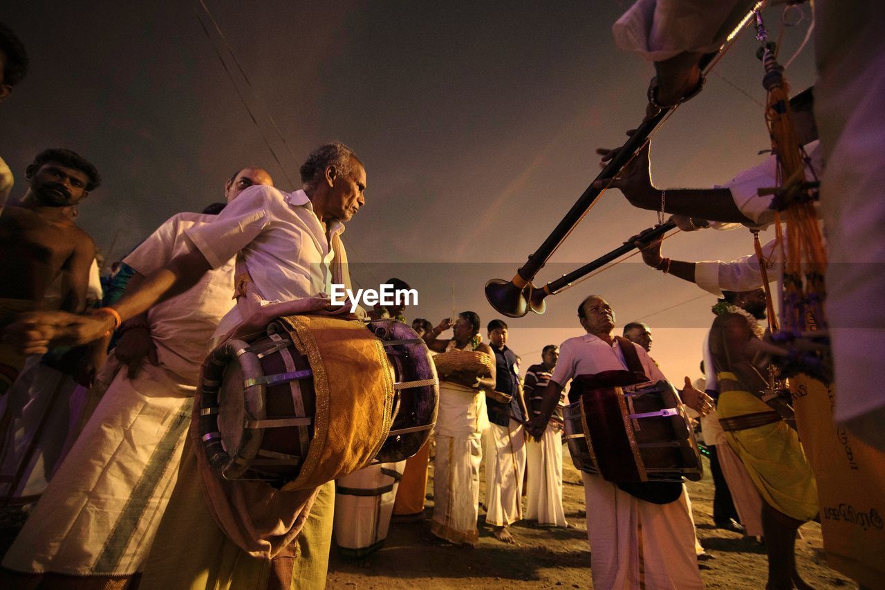 GROUP OF PEOPLE IN TRADITIONAL WINDMILL AGAINST SKY DURING FESTIVAL