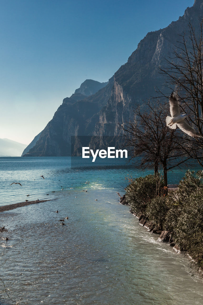 Scenic view of sea and mountains against clear sky