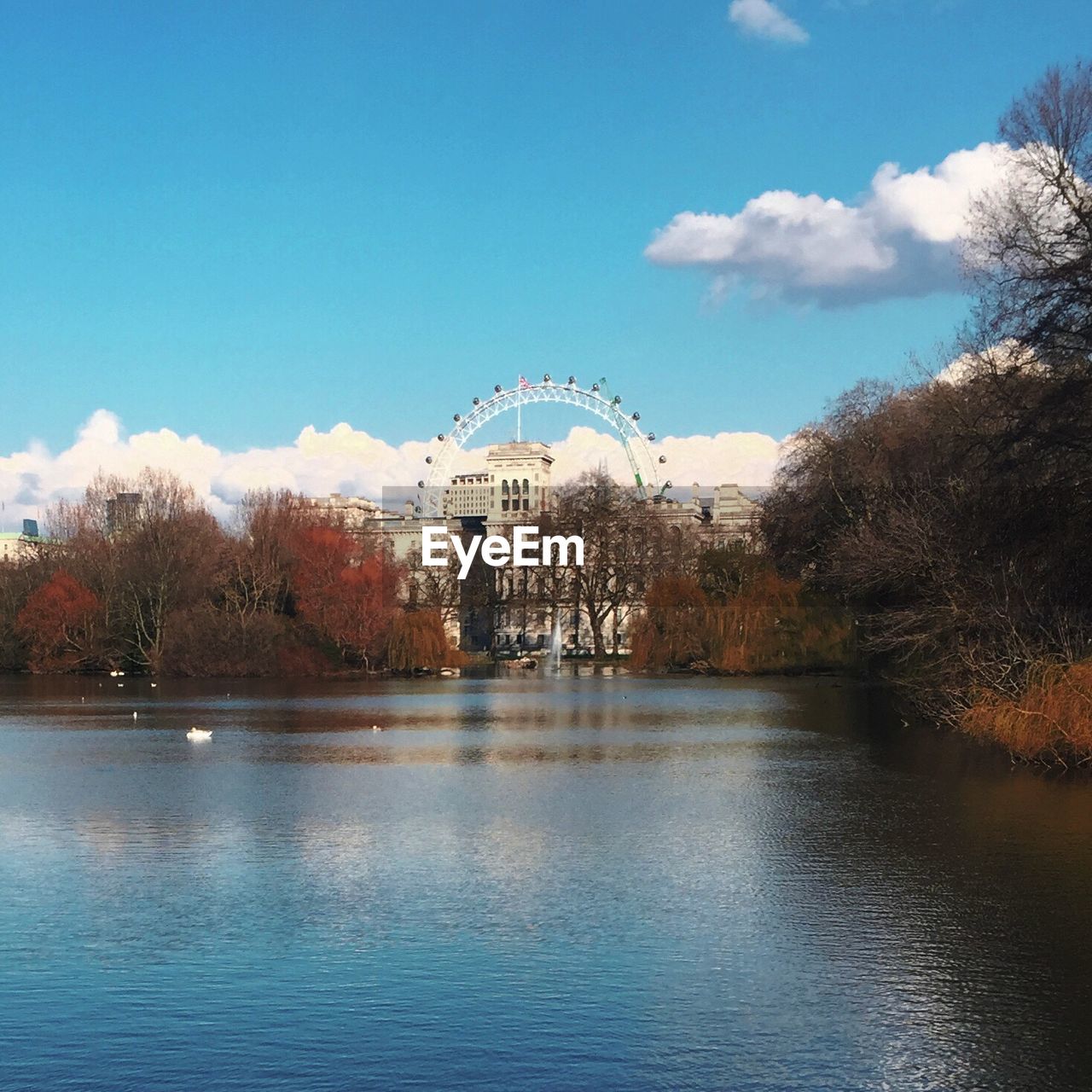 Lake in front of ferris wheel at park against sky