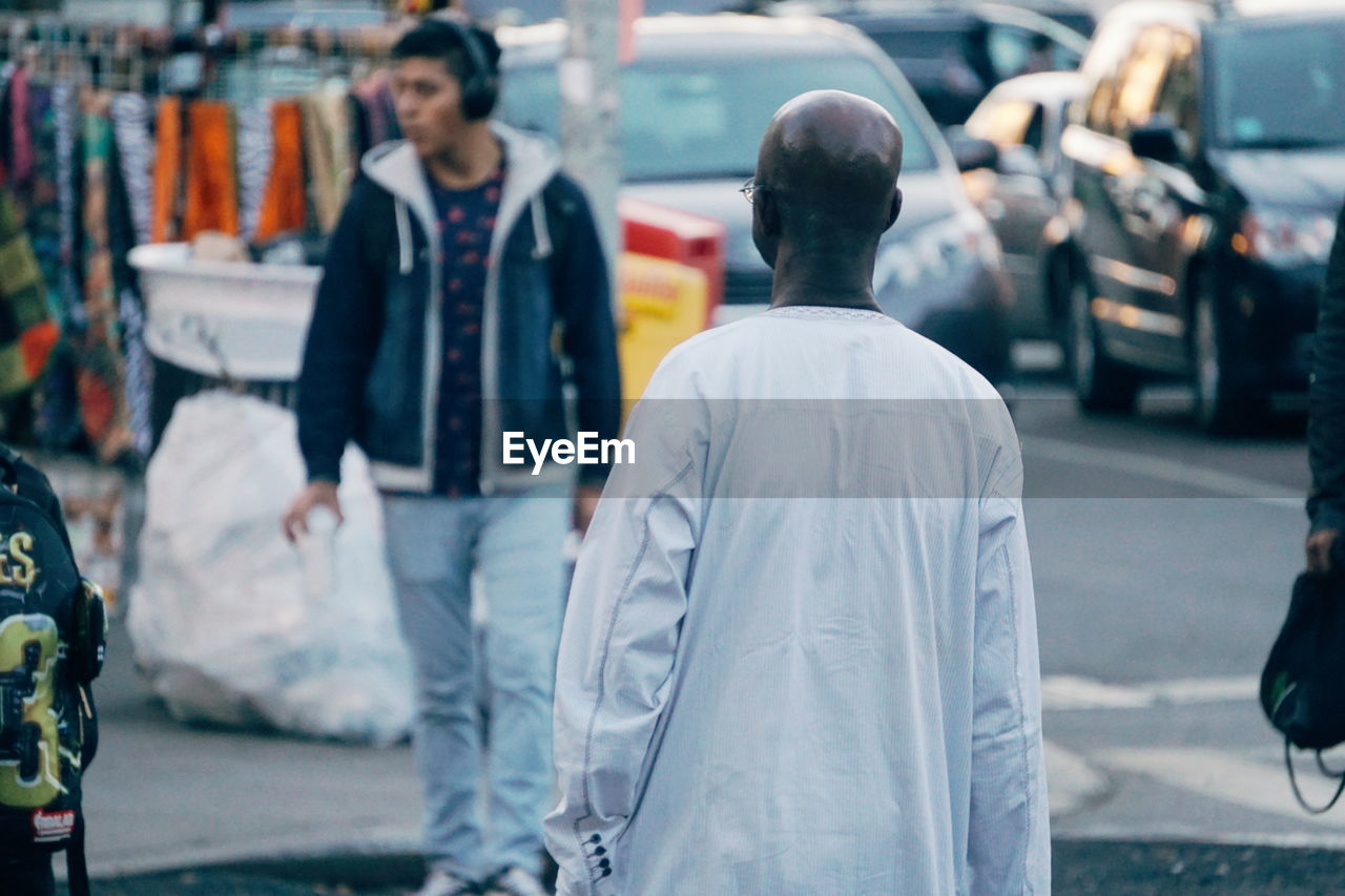 REAR VIEW OF MEN LOOKING AT CITY STREET