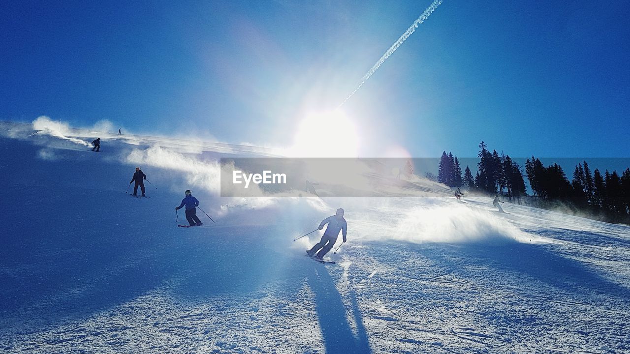 People skiing on snowcapped mountain against sky