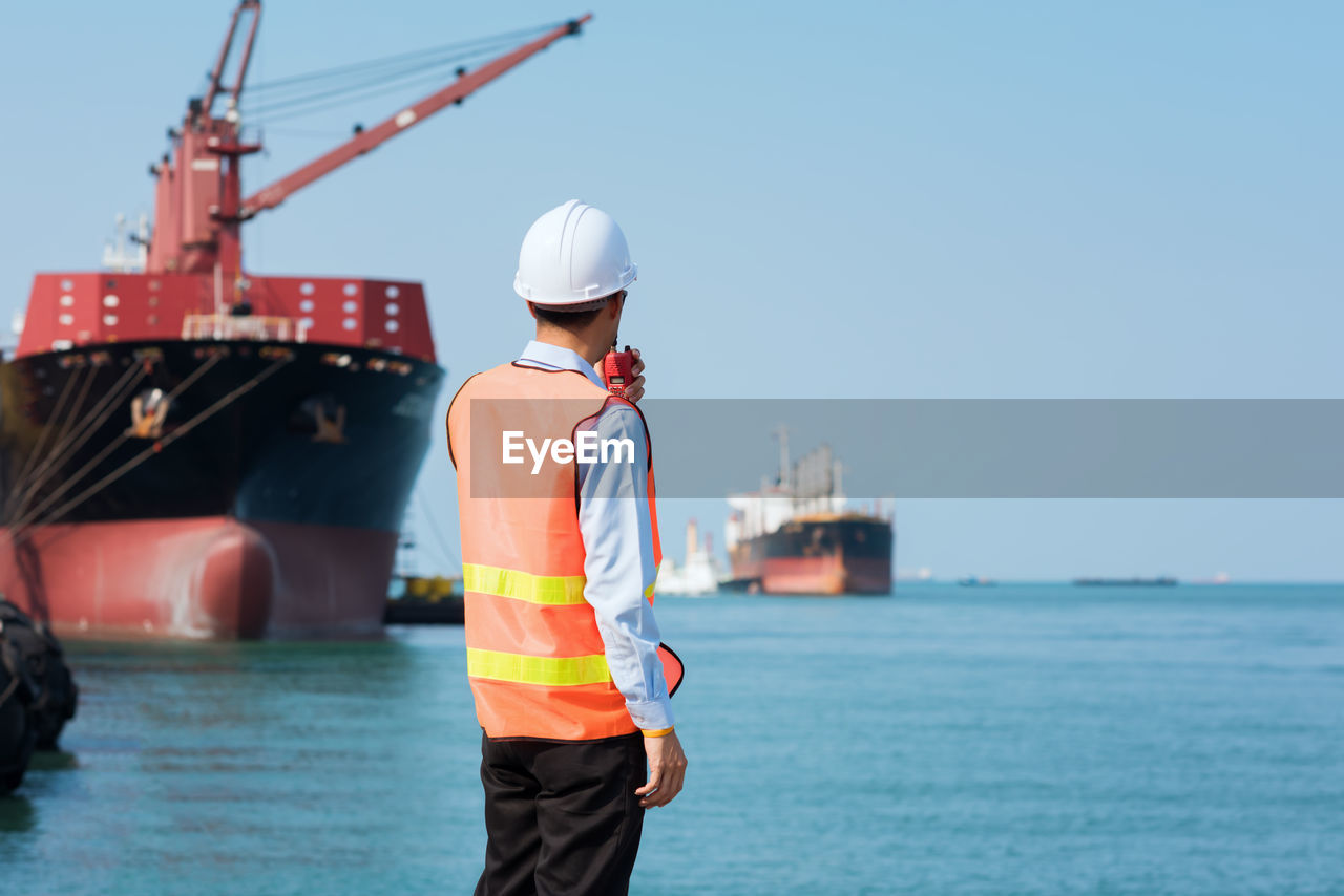 Rear view of man standing at commercial dock