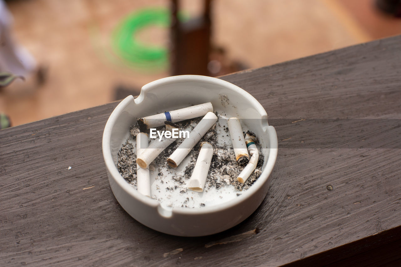 White ceramic ashtray with smoked cigarettes on balcony