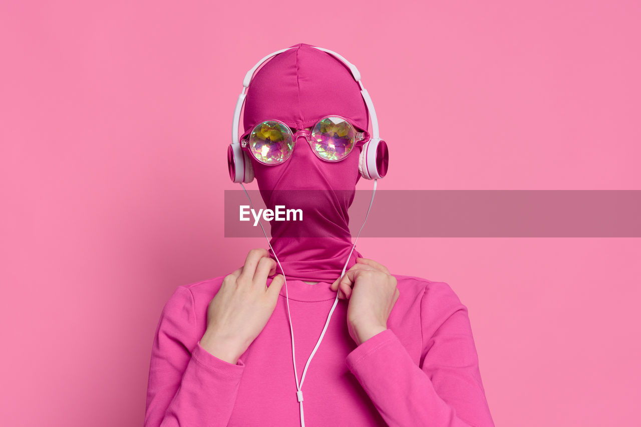 portrait of woman wearing mask against pink background