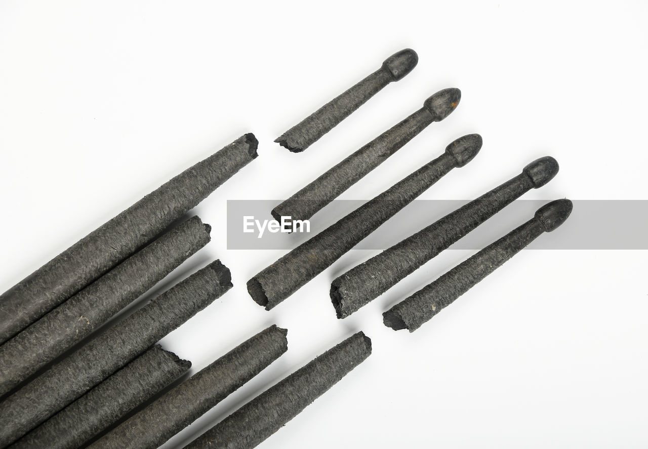 Close-up of broken black wooden drumsticks against white background