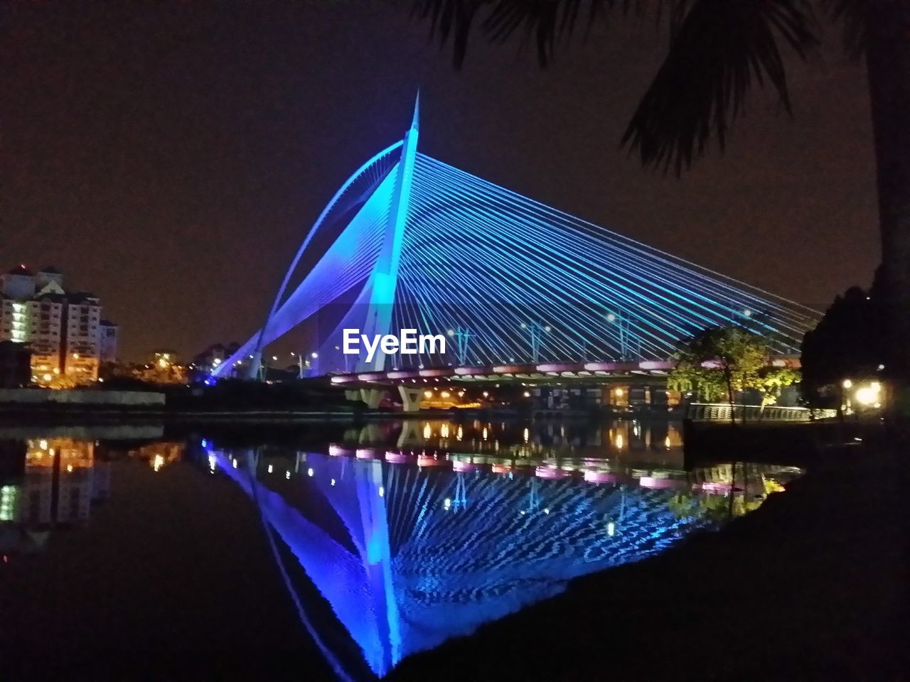 Illuminated city against clear blue sky at night