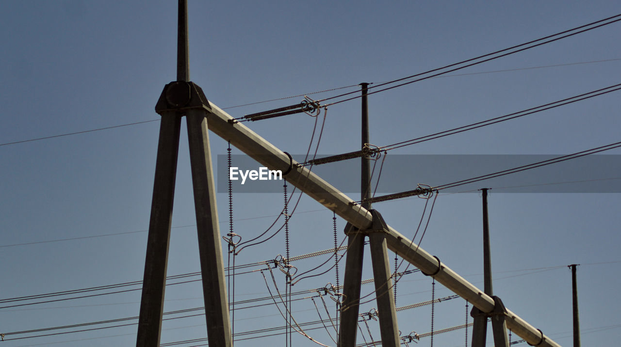 LOW ANGLE VIEW OF ELECTRICITY PYLON AGAINST CLEAR BLUE SKY