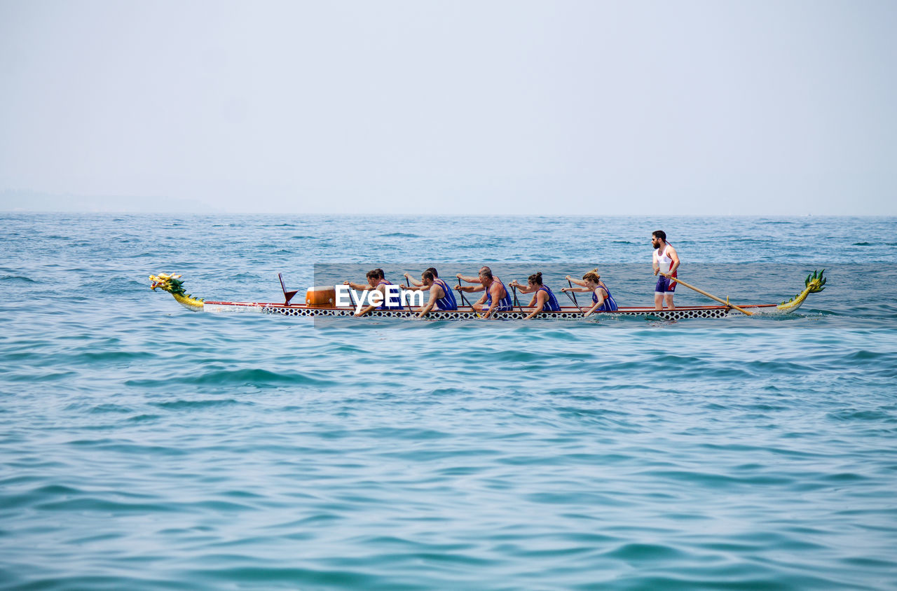 PEOPLE IN SEA AGAINST CLEAR SKY