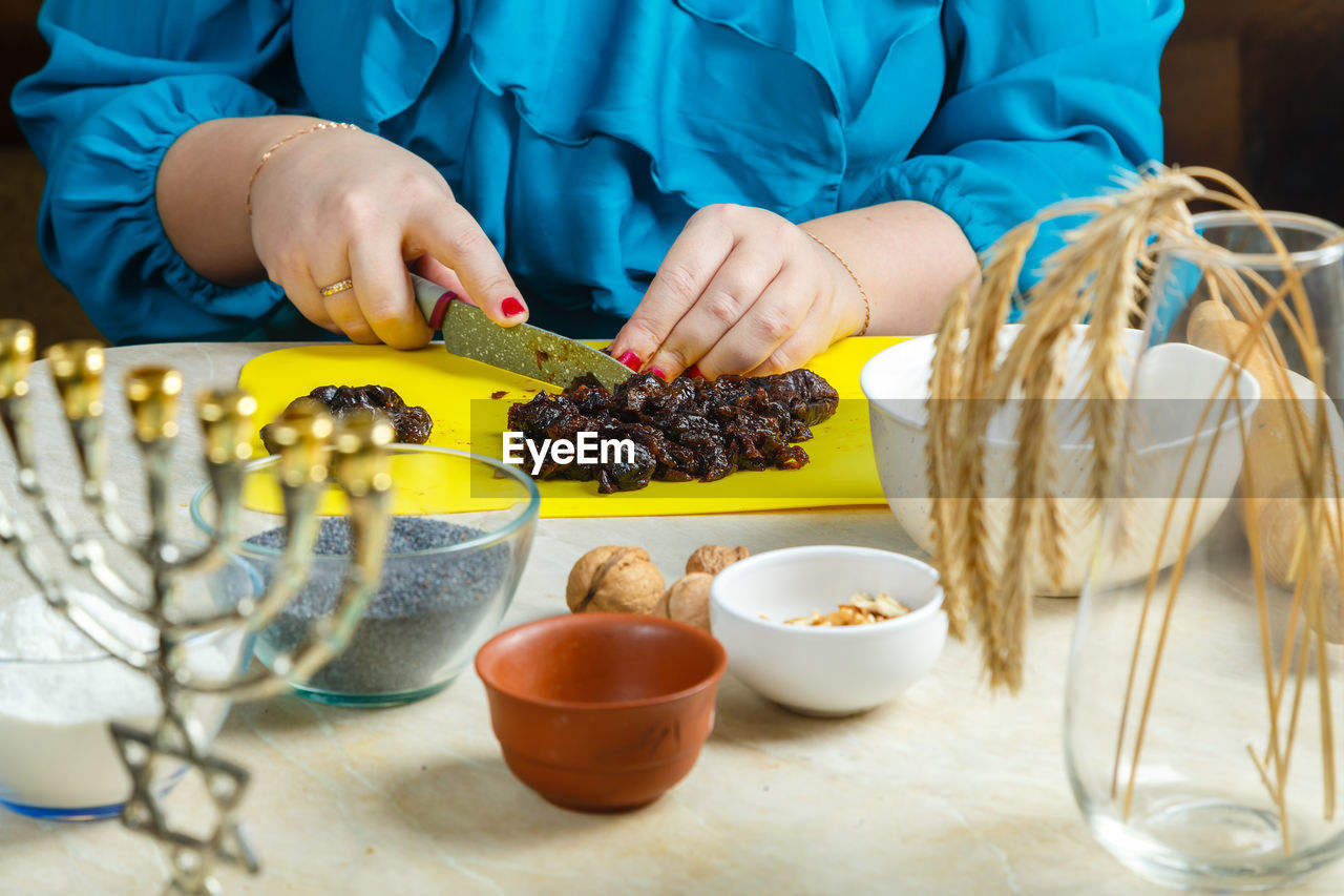 Hands make prunes filling for poppy-seed gomentashi cookies traditional for the jewish holiday purim