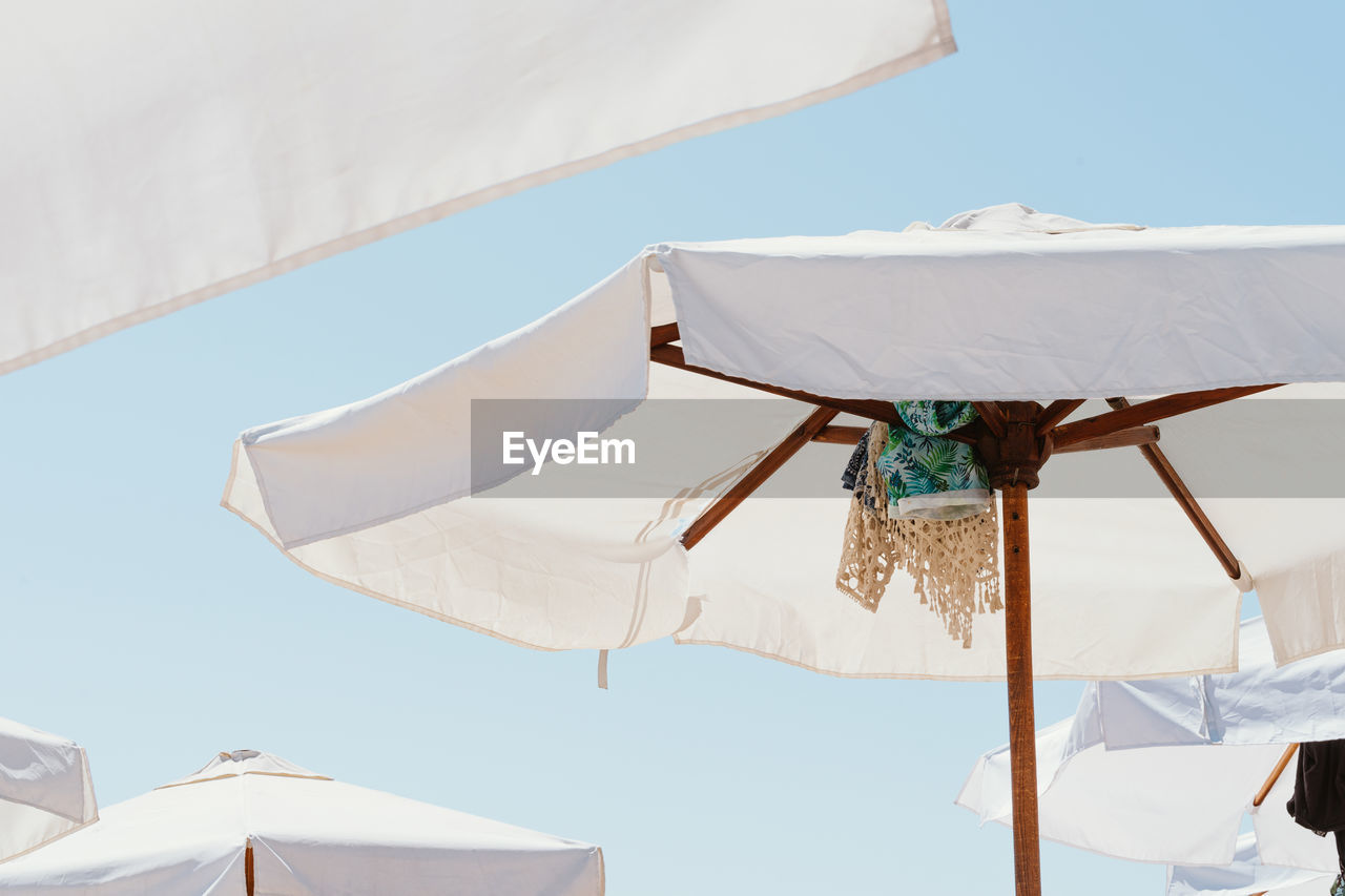 Low angle view of clothes drying on beach umbrella against sky